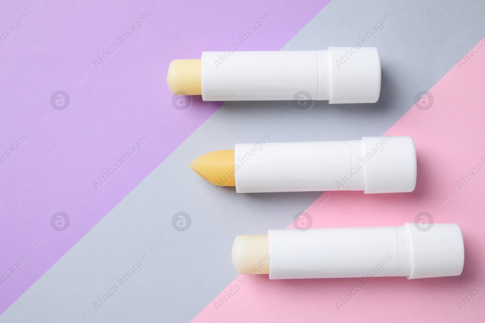 Photo of Hygienic lipsticks on color background, flat lay. Space for text