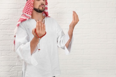 Muslim man praying near brick wall, closeup