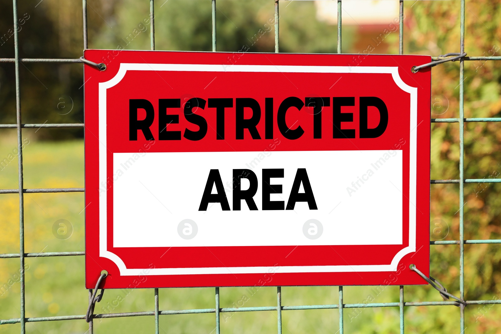 Image of Sign with text Restricted Area on metal fence outdoors
