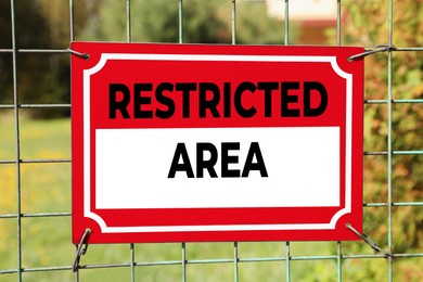 Sign with text Restricted Area on metal fence outdoors