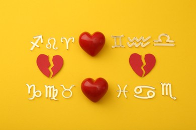 Photo of Zodiac compatibility. Signs with red whole and broken hearts on yellow background, flat lay