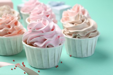 Delicious birthday cupcakes and sprinkles on turquoise background, closeup