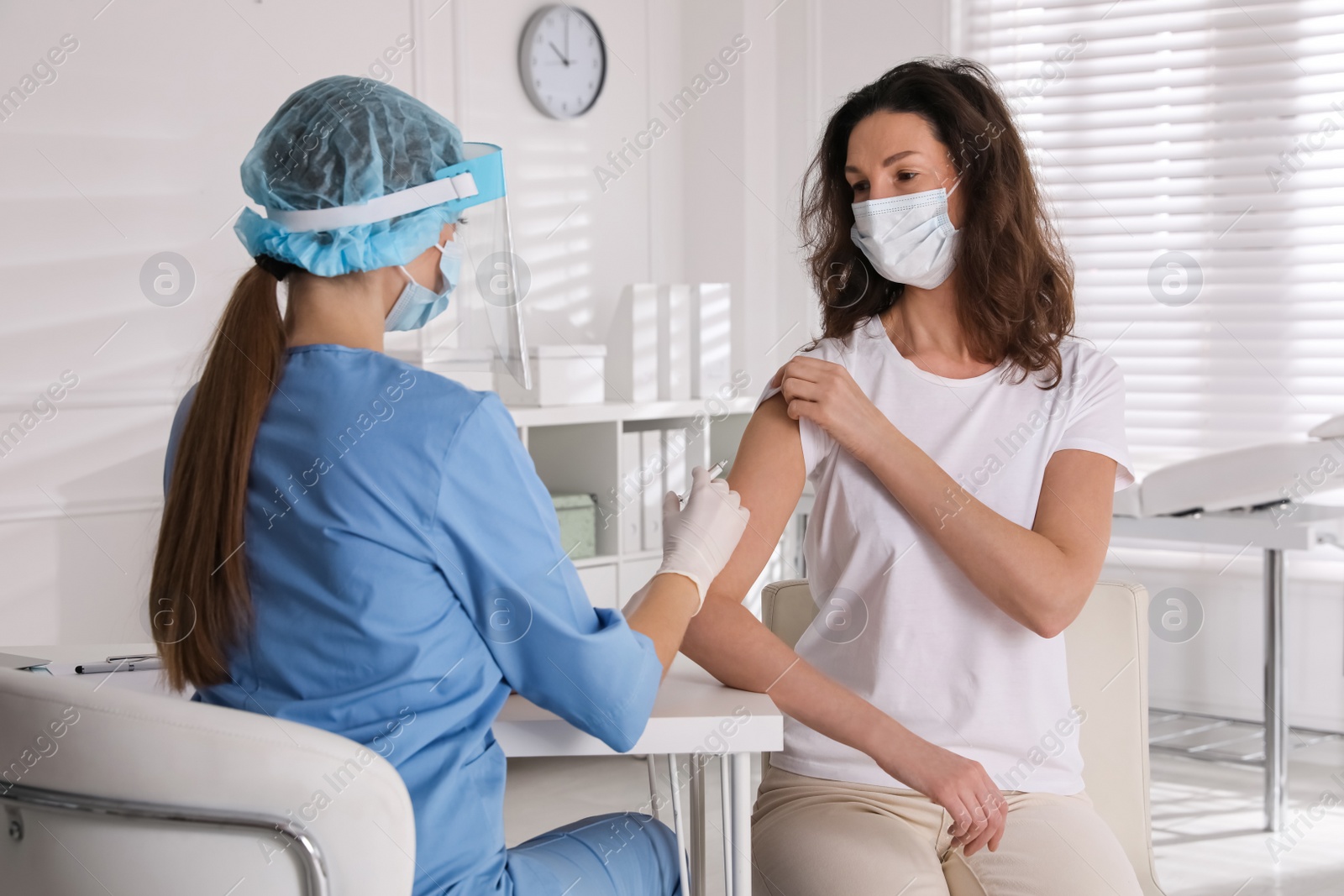 Photo of Doctor vaccinating mature woman against Covid-19 in clinic