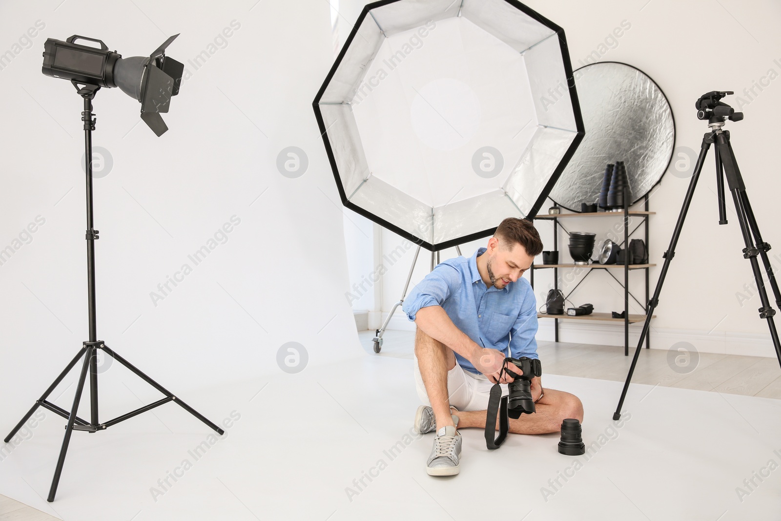 Photo of Professional photographer with camera and lighting equipment in studio