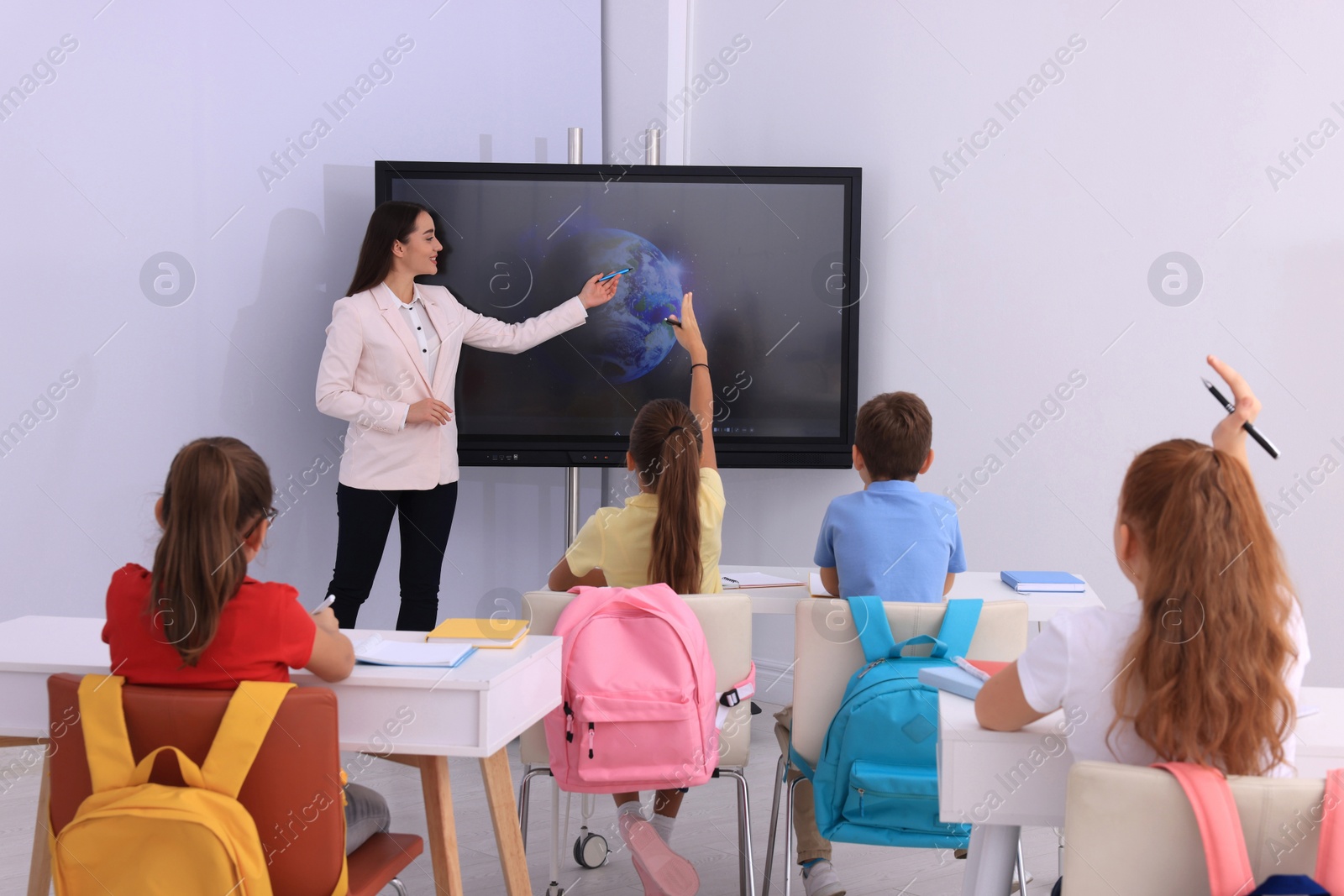 Photo of Teacher using interactive board in classroom during lesson