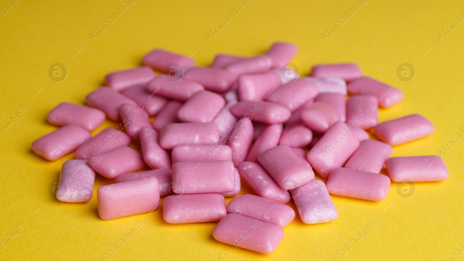 Photo of Pile of sweet chewing gums on yellow background