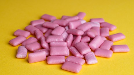 Photo of Pile of sweet chewing gums on yellow background