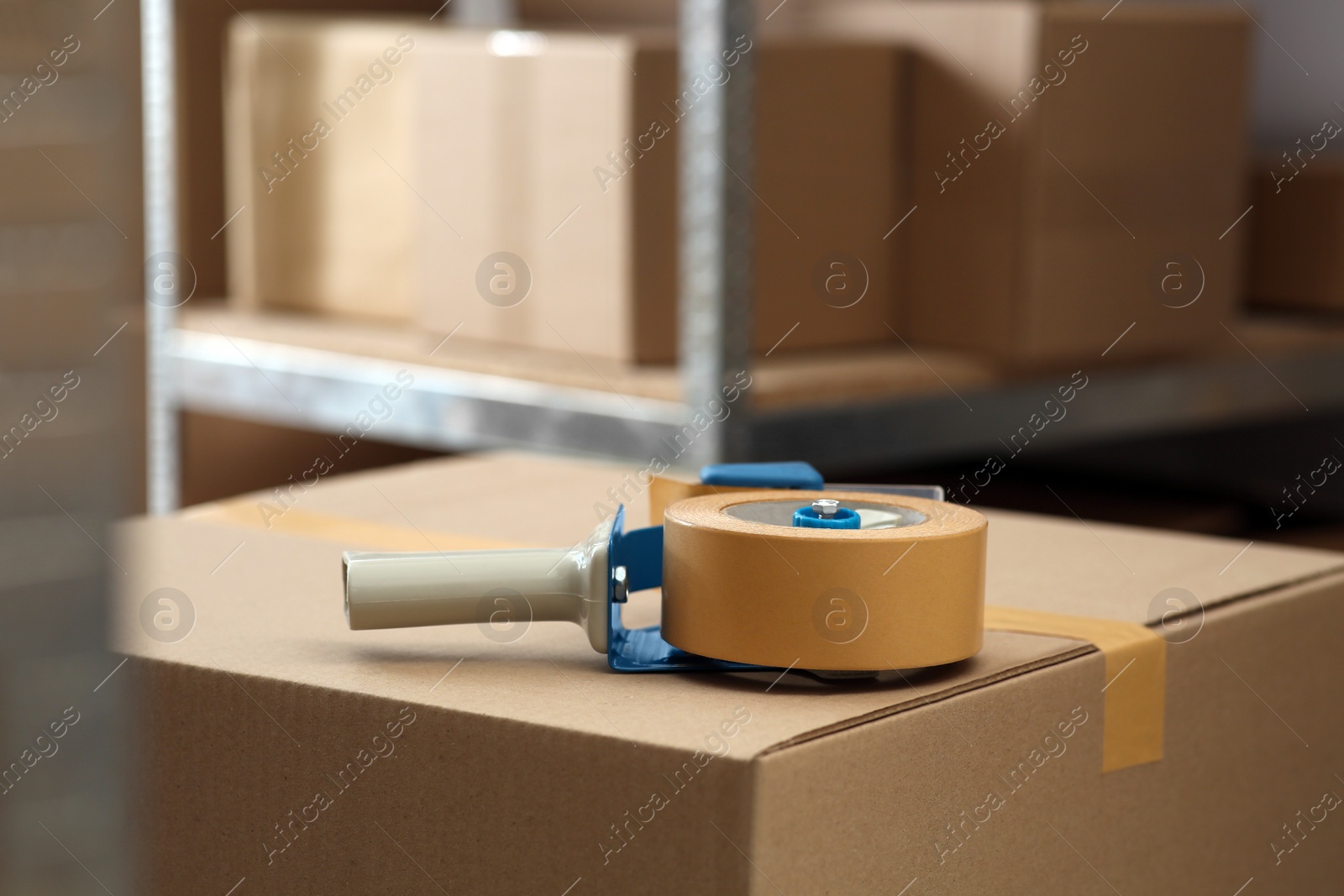 Photo of Adhesive tape dispenser on cardboard box indoors