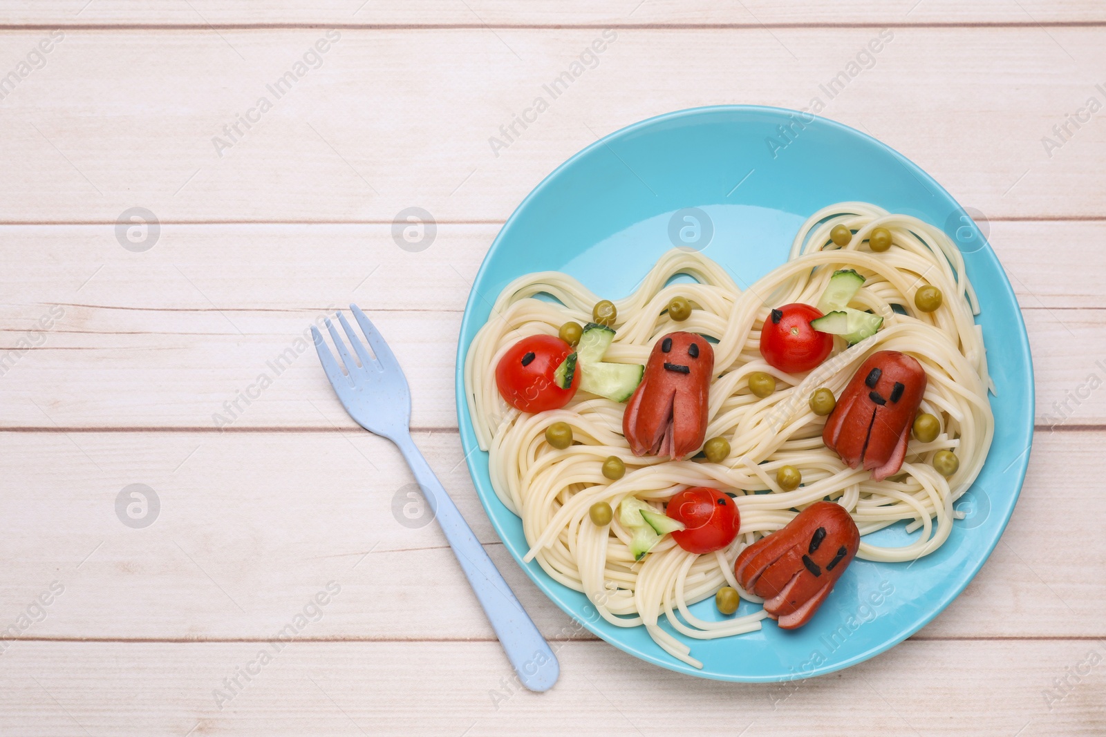 Photo of Creative serving for kids. Plate with cute octopuses made of sausages, pasta and vegetables on white wooden table, flat lay. Space for text