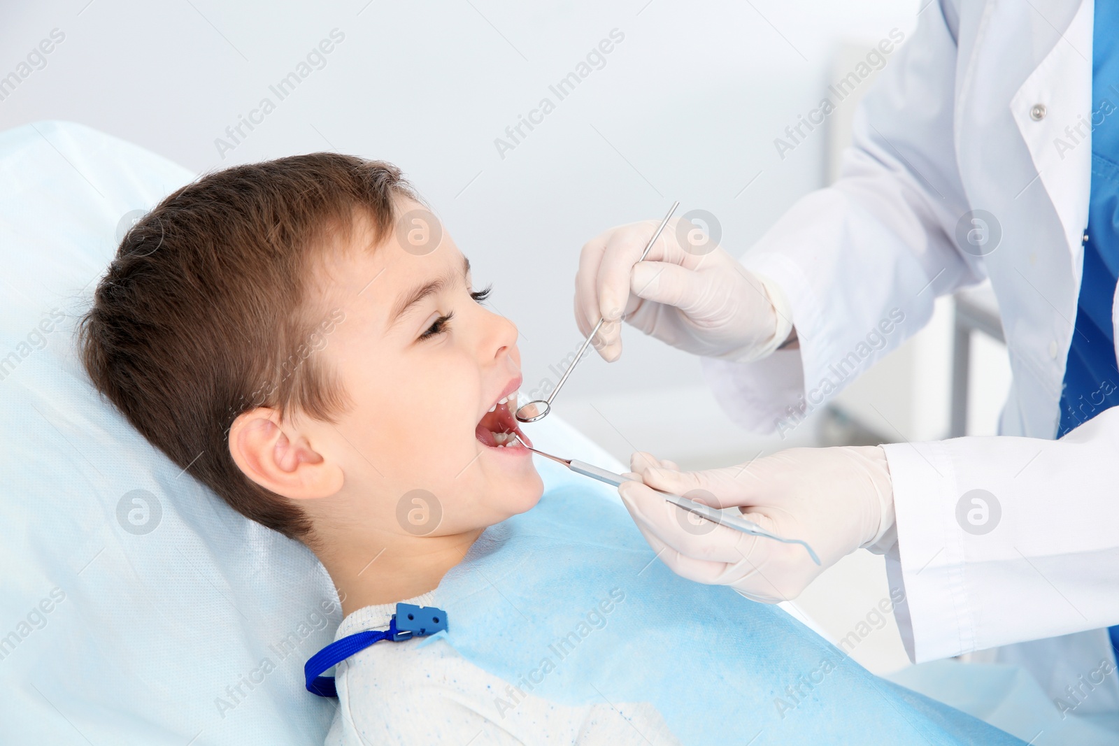 Photo of Dentist examining cute boy's teeth in modern clinic