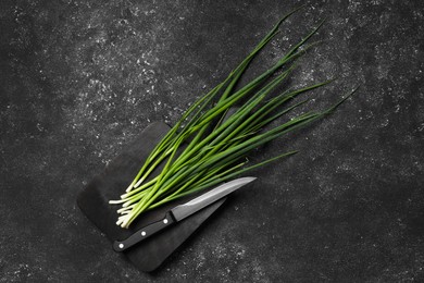 Photo of Fresh green onion and knife on black table, top view. Space for text