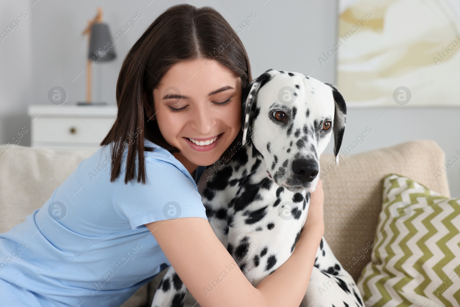 Photo of Beautiful woman hugging her adorable Dalmatian dog on sofa at home. Lovely pet