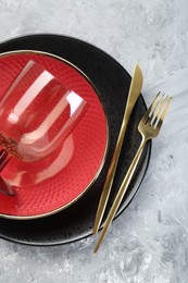 Photo of Clean plates, glass and cutlery on gray textured table, top view