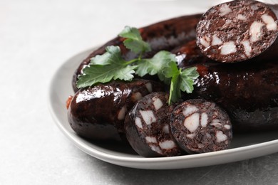 Photo of Tasty blood sausages with parsley served on light grey table, closeup
