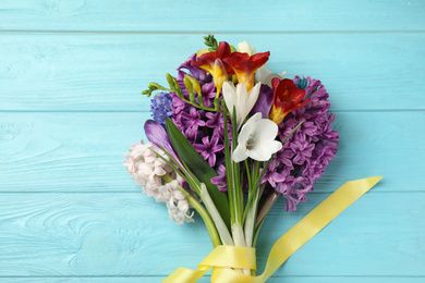 Photo of Bouquet of beautiful spring flowers on blue wooden table, top view