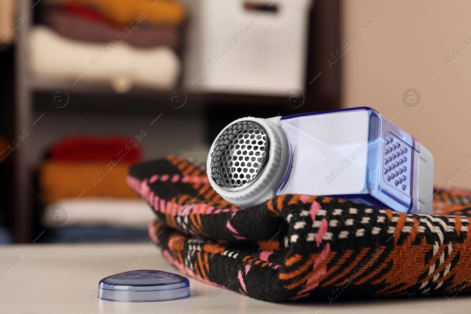 Photo of Modern fabric shaver and cloth on white table indoors, closeup. Space for text