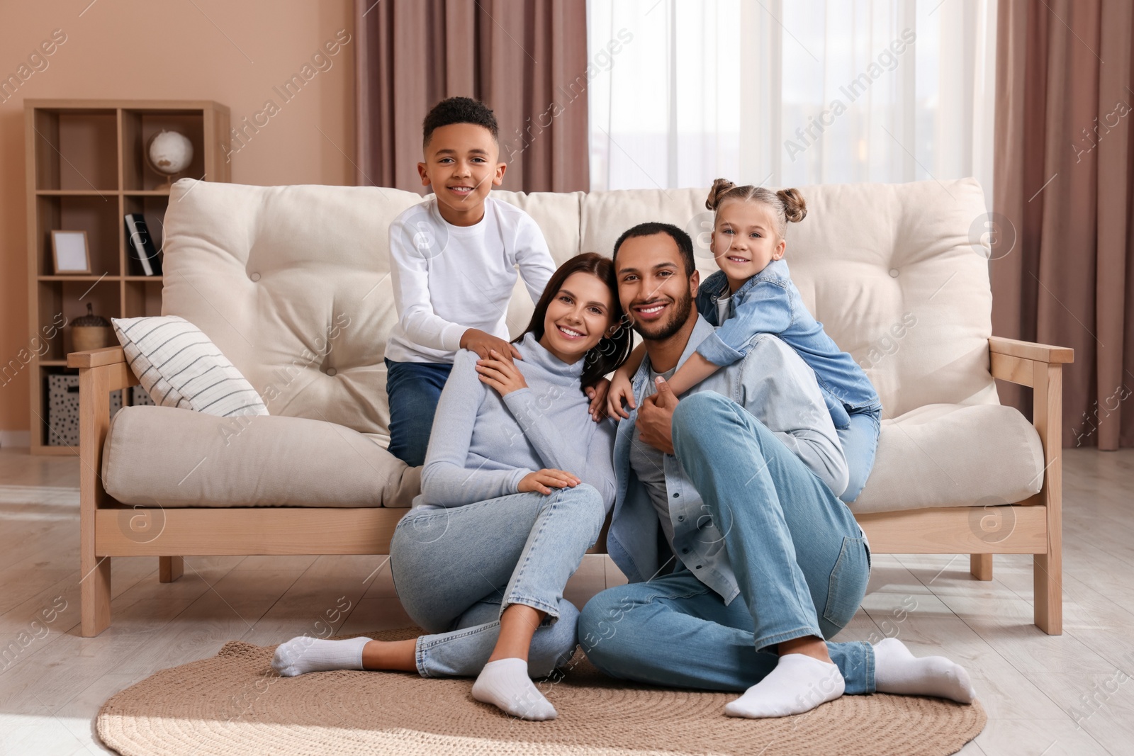 Photo of Happy international family with children near sofa at home