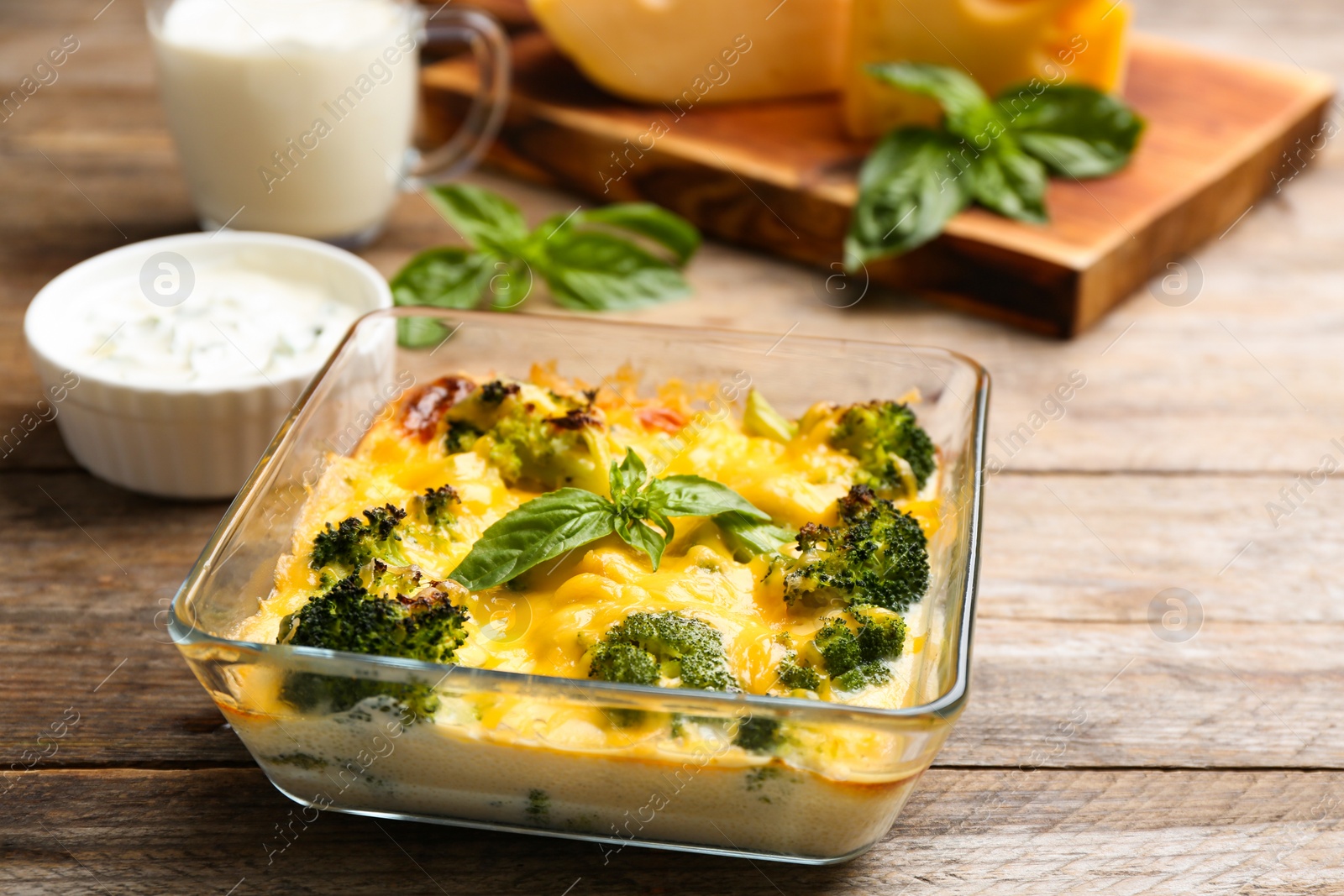 Photo of Tasty broccoli casserole in baking dish on wooden table