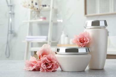 Photo of Hair care cosmetic products and beautiful flowers on light grey table in bathroom, space for text