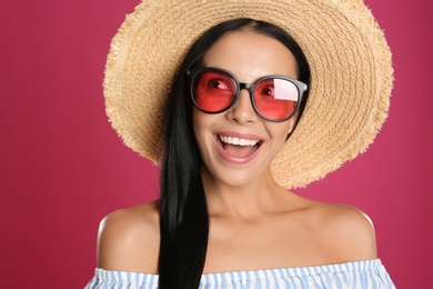 Beautiful woman wearing sunglasses on pink background, closeup