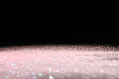 Photo of Shiny pink glitter on black background, space for text. Bokeh effect