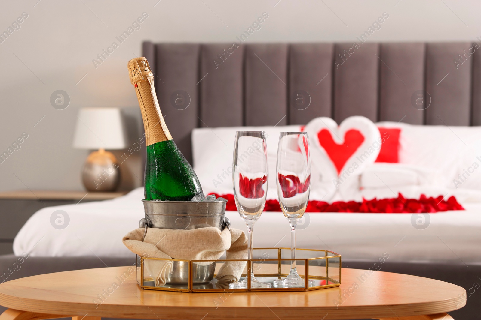 Photo of Honeymoon. Sparkling wine and glasses on wooden table in room