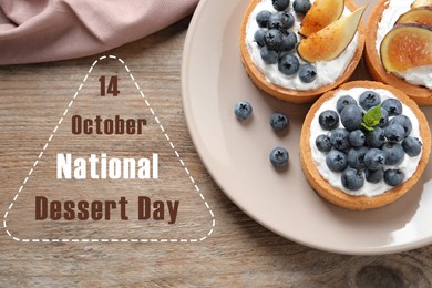 Image of National Dessert Day, October 14. Tasty tartlets with blueberries and figs on wooden table, flat lay