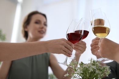 Photo of Young people with glasses of delicious wine indoors