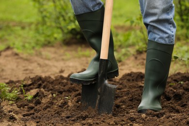 Photo of Worker digging soil with shovel outdoors, closeup. Gardening tool