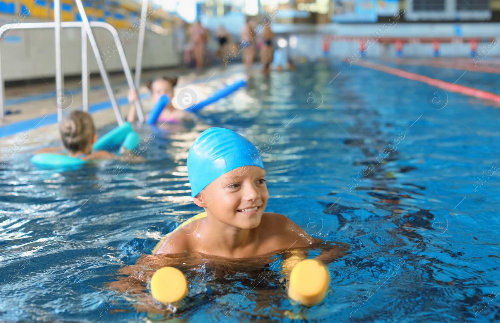 Photo of Little boy with swimming noodle in indoor pool