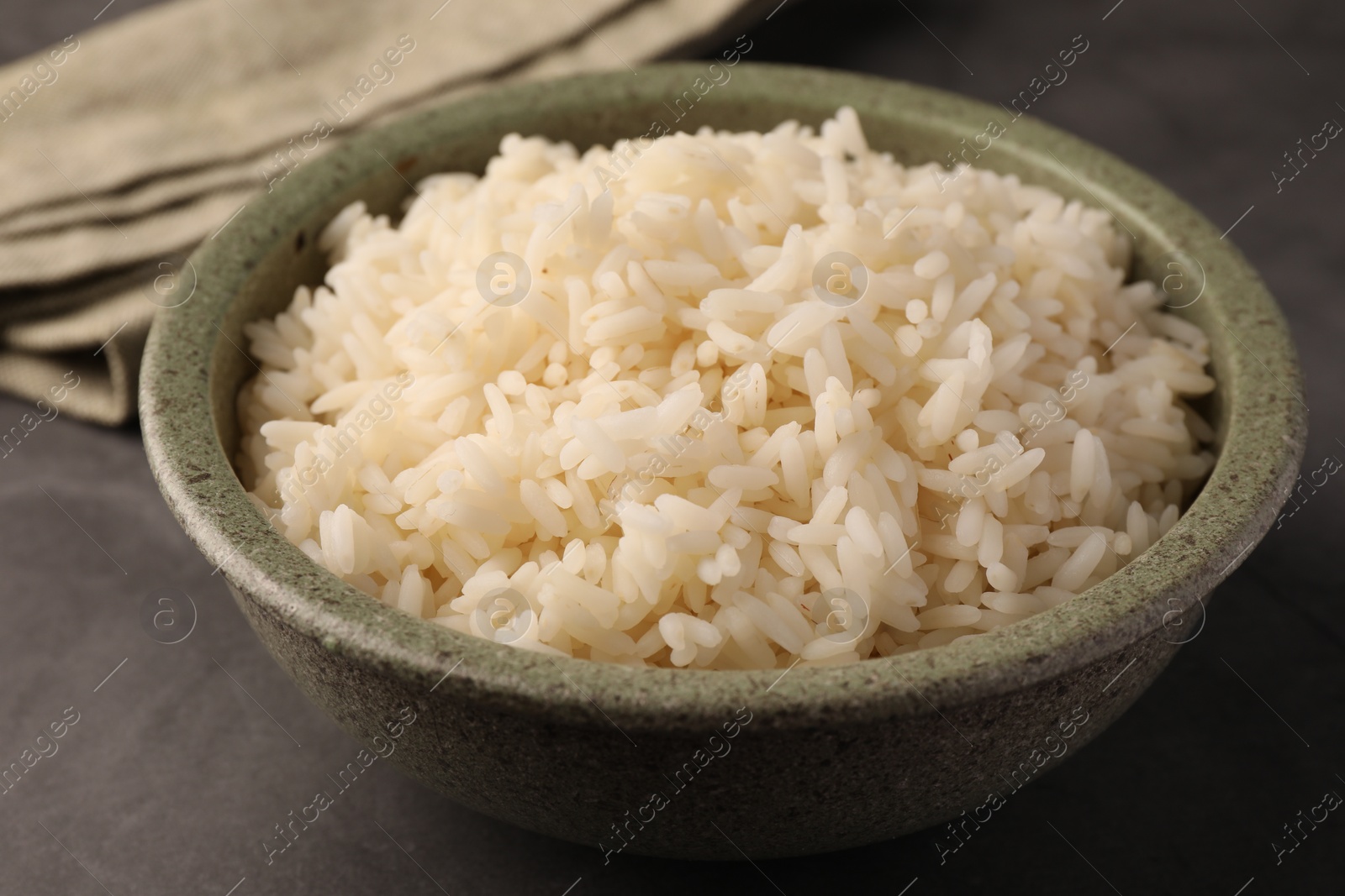 Photo of Delicious rice in bowl on grey table, closeup