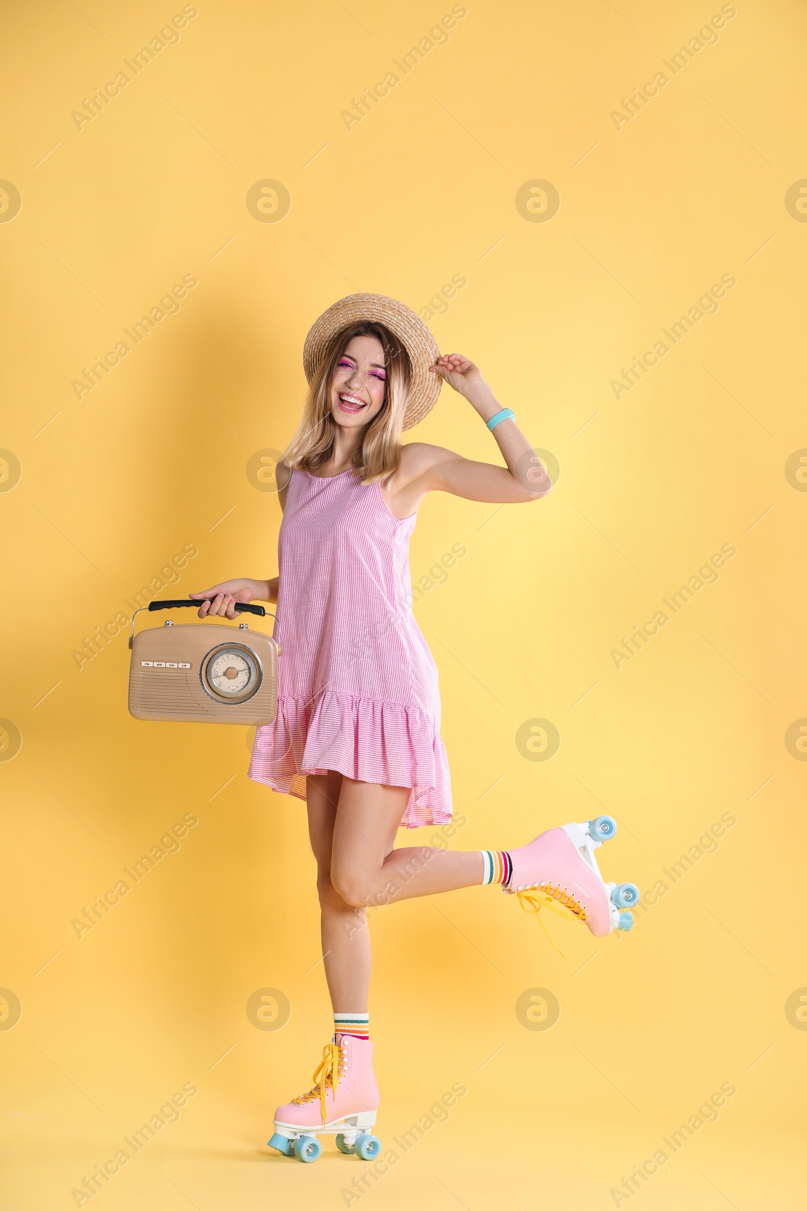 Photo of Young woman with roller skates and retro radio on color background