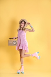 Young woman with roller skates and retro radio on color background