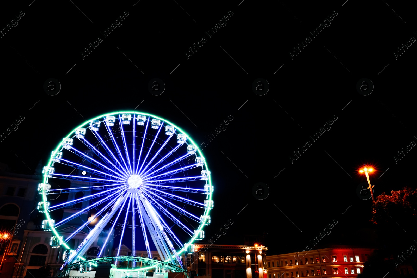 Photo of Beautiful glowing Ferris wheel against dark sky, low angle view. Space for text