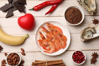 Photo of Natural aphrodisiac. Different food products and red decorative heart on light wooden table, flat lay