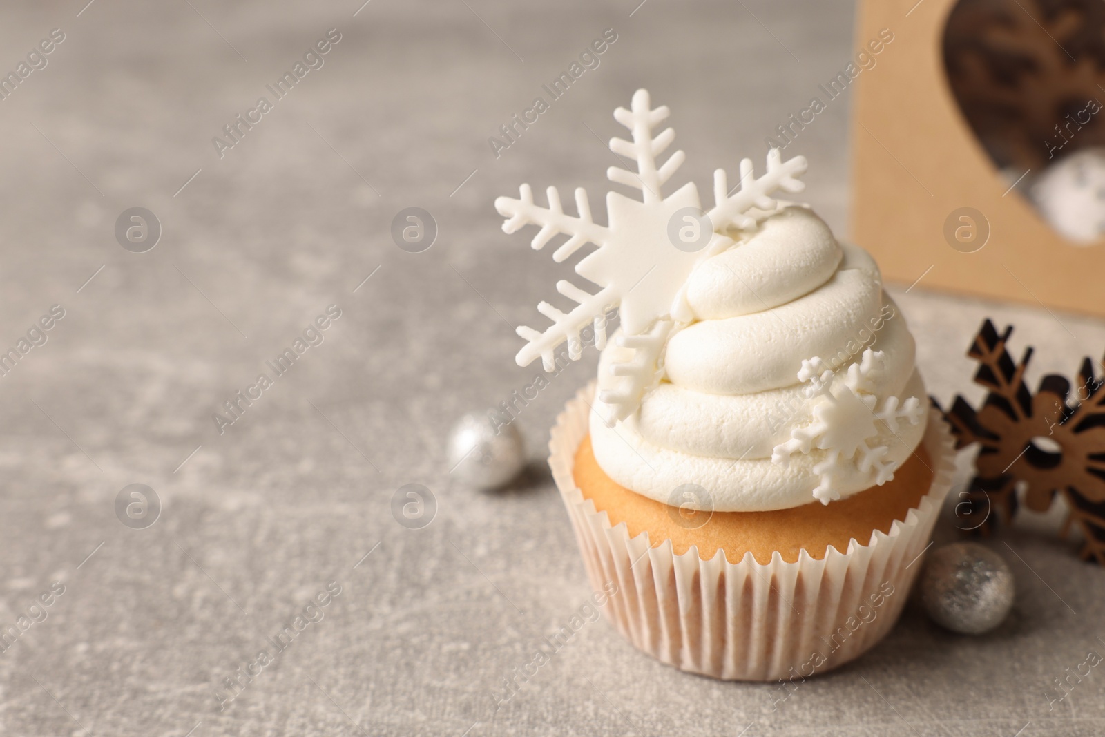 Photo of Tasty Christmas cupcake with snowflakes and festive decor on grey table. Space for text