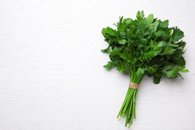 Photo of Bunch of fresh green parsley on white wooden table, top view. Space for text