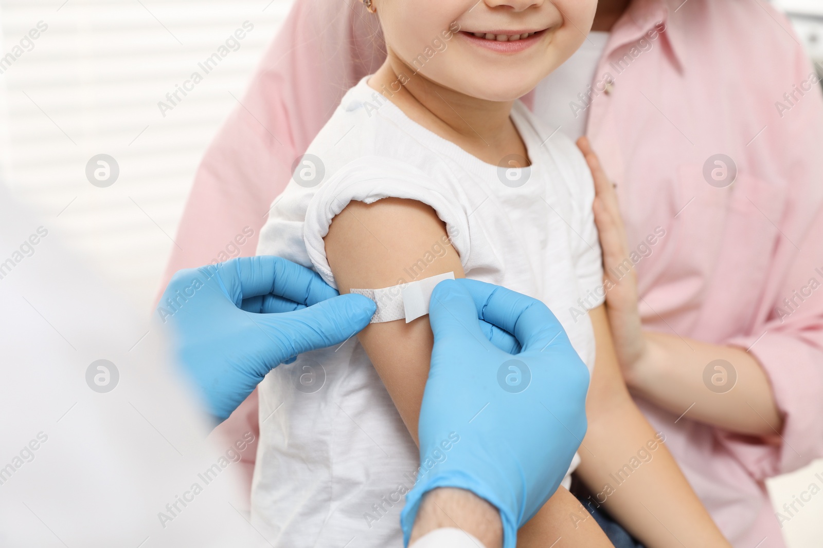 Photo of Children's hepatitis vaccination. Mother with her daughter in clinic. Doctor sticking medical plaster on little girl's arm, closeup