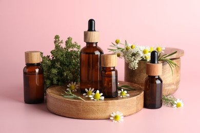 Photo of Aromatherapy. Different essential oils and flowers on pink background