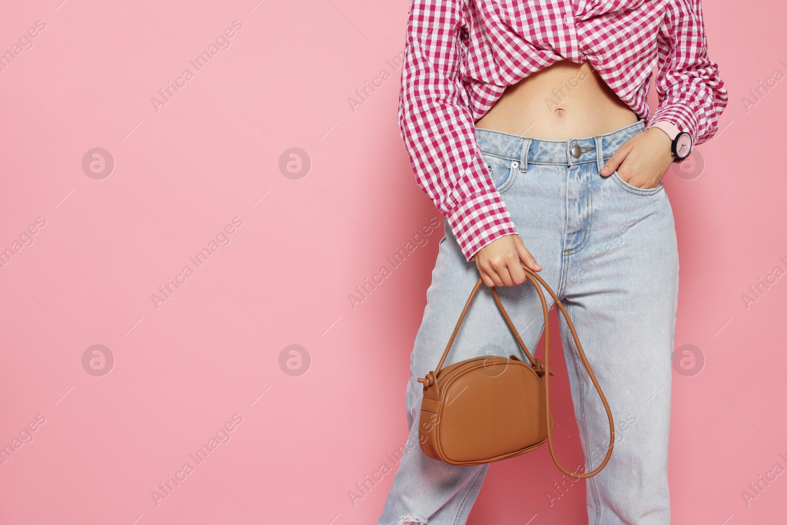Photo of Woman in fashionable outfit with stylish bag on pink background, closeup. Space for text