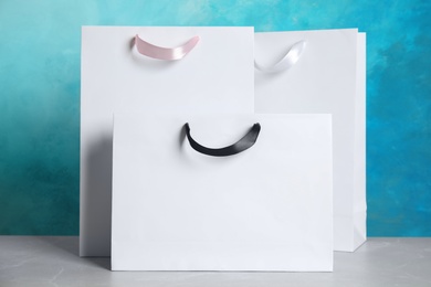 Photo of Paper shopping bags on table against color background. Mock up for design