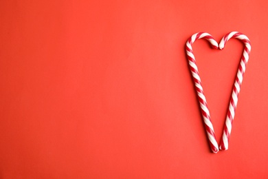 Photo of Candy canes on red background, flat lay. Space for text