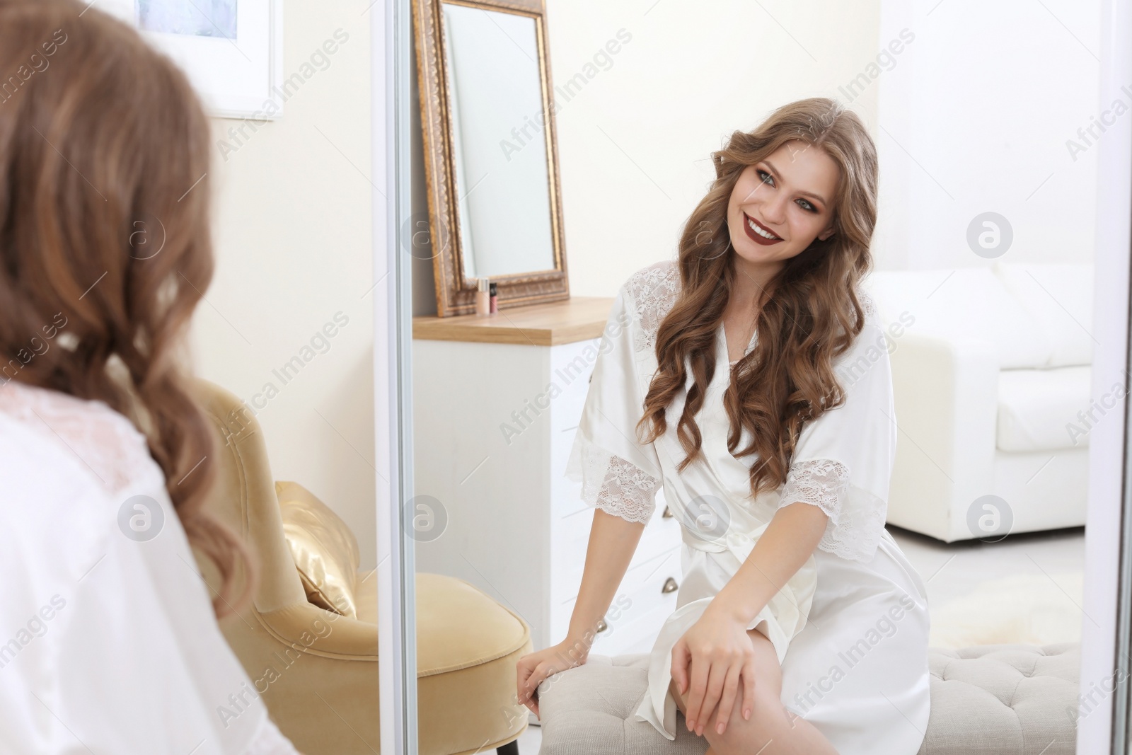 Photo of Young beautiful woman near mirror in makeup room