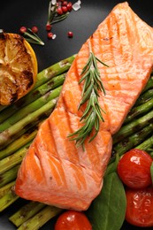 Tasty grilled salmon with tomatoes, asparagus and spices on plate, top view