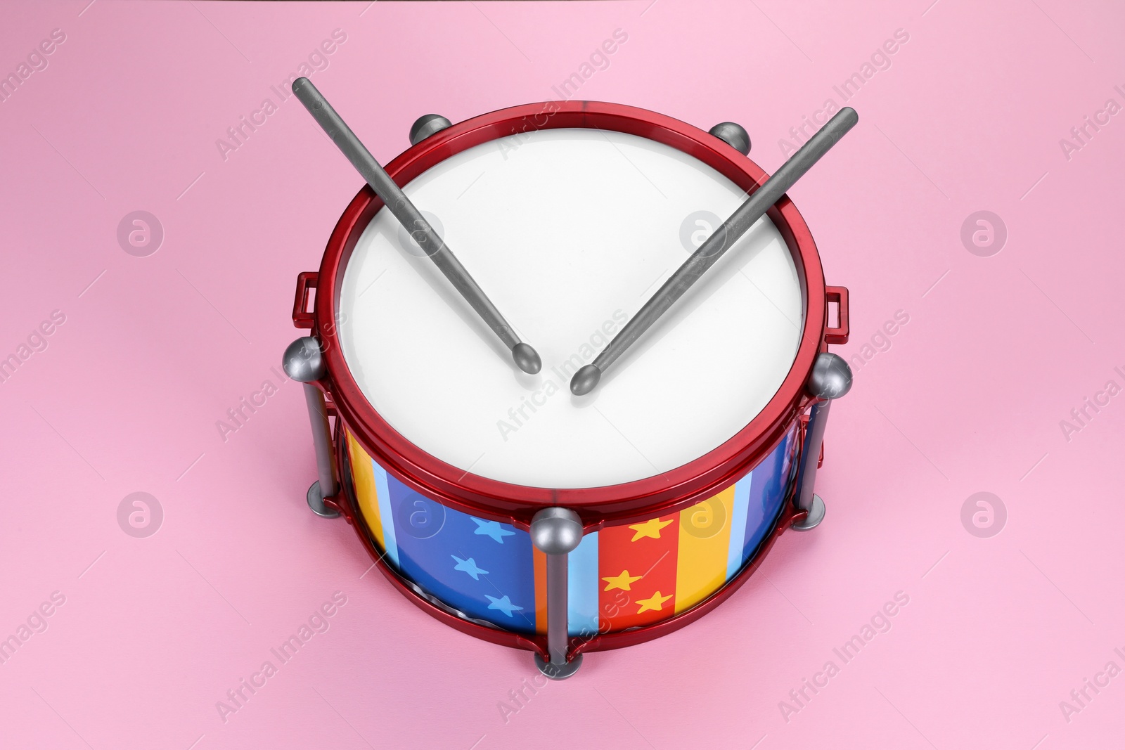 Photo of Children's drum with drumsticks on pink background