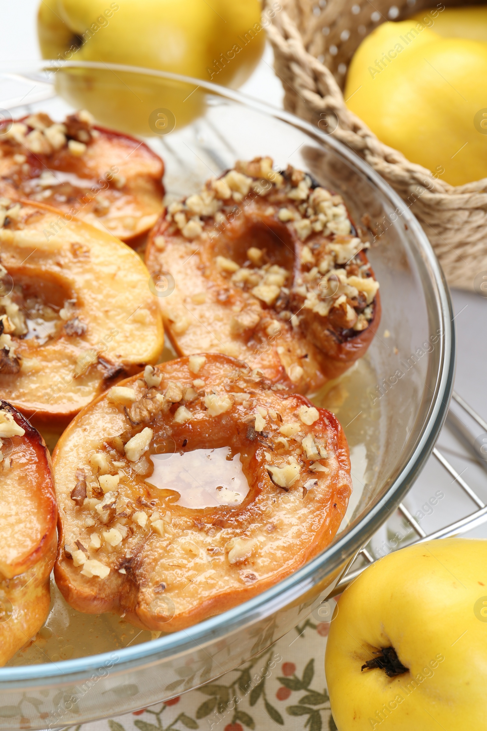 Photo of Delicious baked quinces with nuts in bowl and fresh fruits on table, closeup