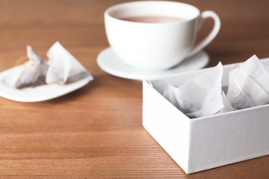 Photo of Box with pyramid teabags and cup on table. Space for text