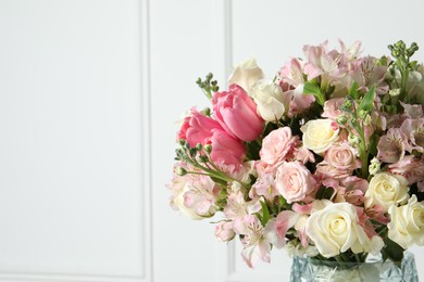 Beautiful bouquet of fresh flowers in vase near white wall. Space for text