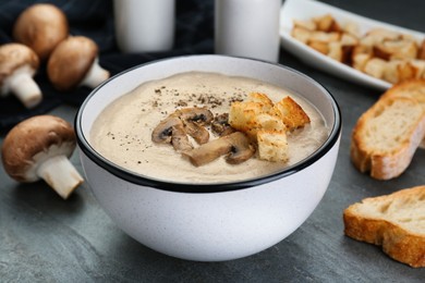 Delicious cream soup with mushrooms and croutons on black table, closeup
