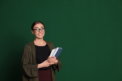 Photo of Portrait of young teacher with books on green background. Space for text